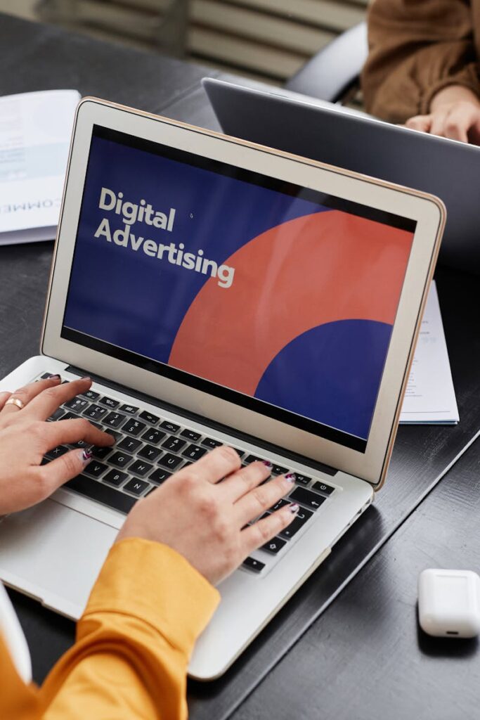 Two professionals work on laptops focusing on digital advertising in an office setting.